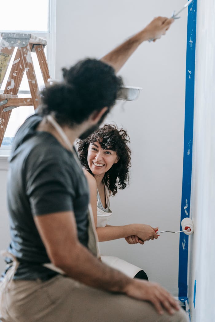 A joyful couple renovating their home together with paint rollers indoors.